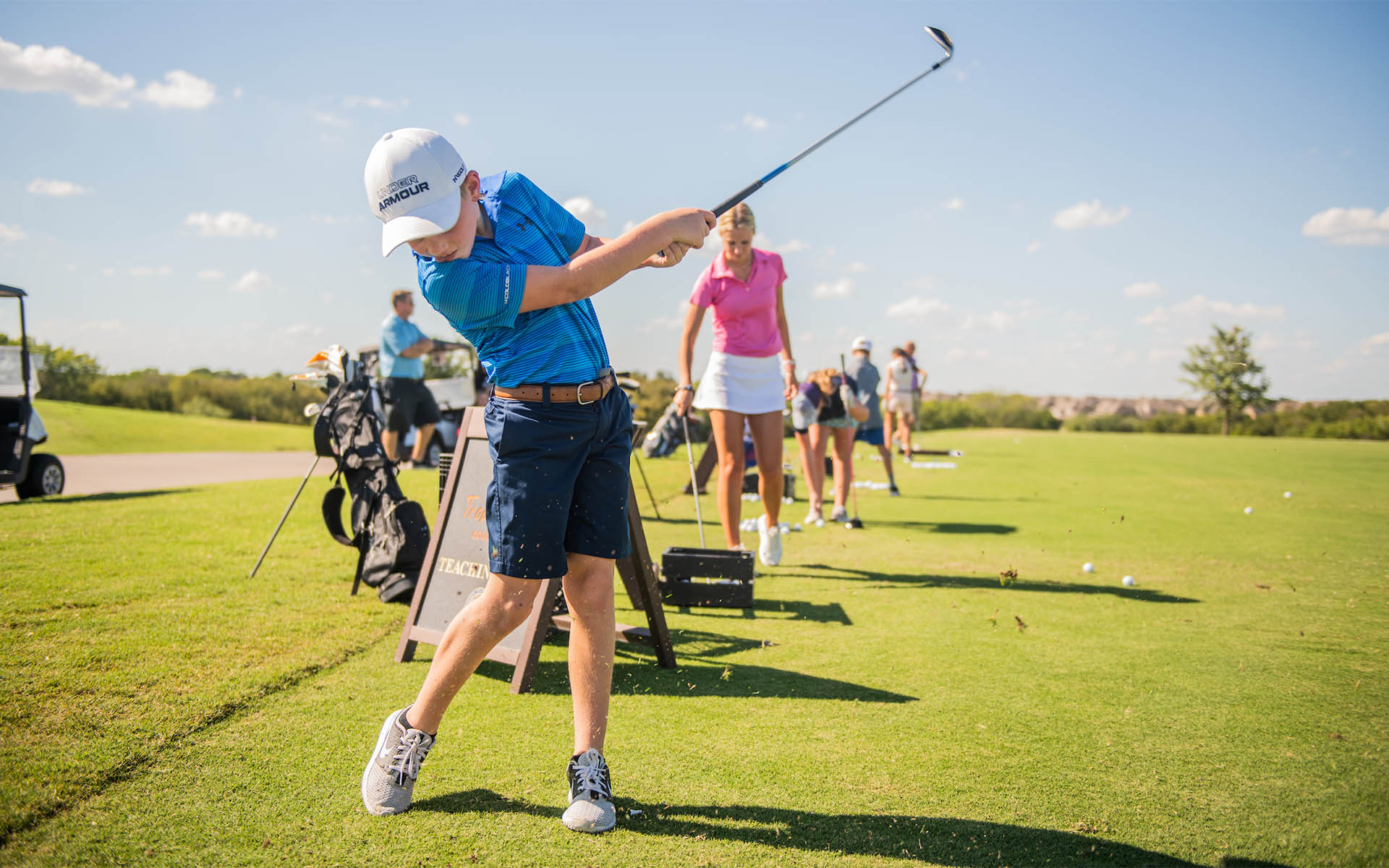 Youth golfers working to improve their skills at an Invited Club driving range, embracing the essence of our comprehensive youth golf program.